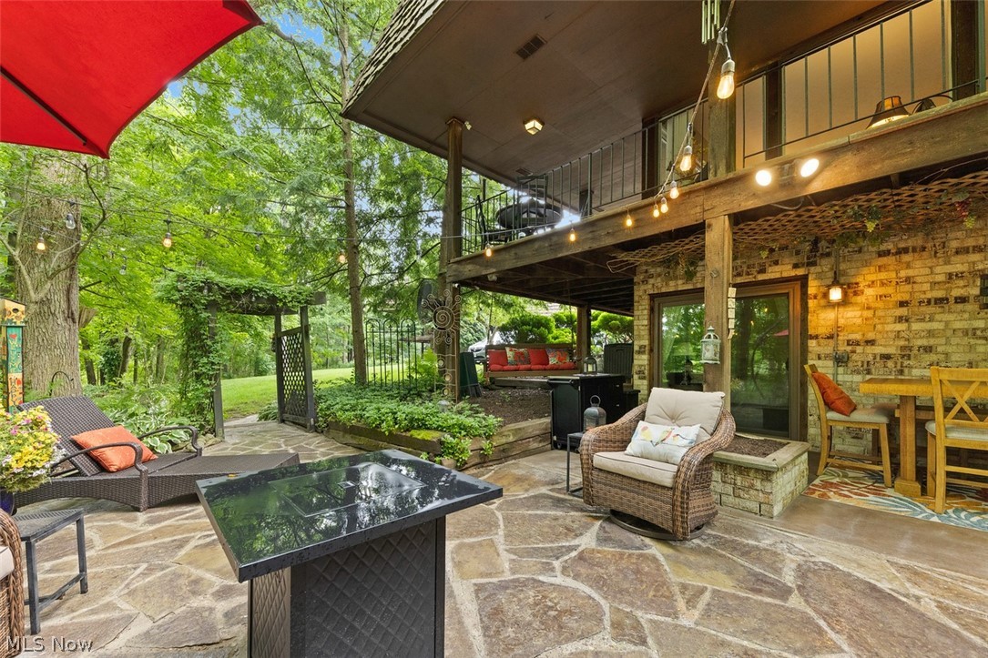 171 Granger Road, Unit 107 Medina, OH 44256 - Photo 37 of 41 Flagstone patio with a fire table ( that stays) brick exterior wall, and multiple glass-paneled doors. The trellis over the walkway stays.
