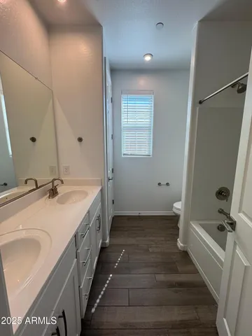 a bathroom with a double vanity sink a mirror and a bathtub