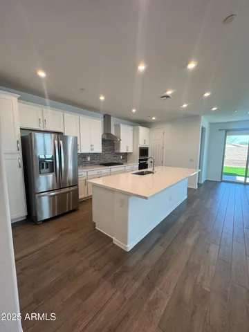 a large kitchen with stainless steel appliances kitchen island a large counter top and wooden floors
