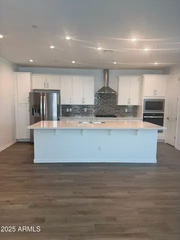 a large kitchen with stainless steel appliances a large counter top a stove and a refrigerator