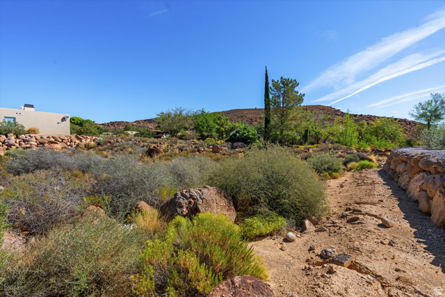 240 Boulder Way, Unit 3 Leeds, UT 84746 - Photo 12 of 12 Natural desert landscaping with a stone retaining wall, expansive rocky terrain, and a distant stucco exterior structure