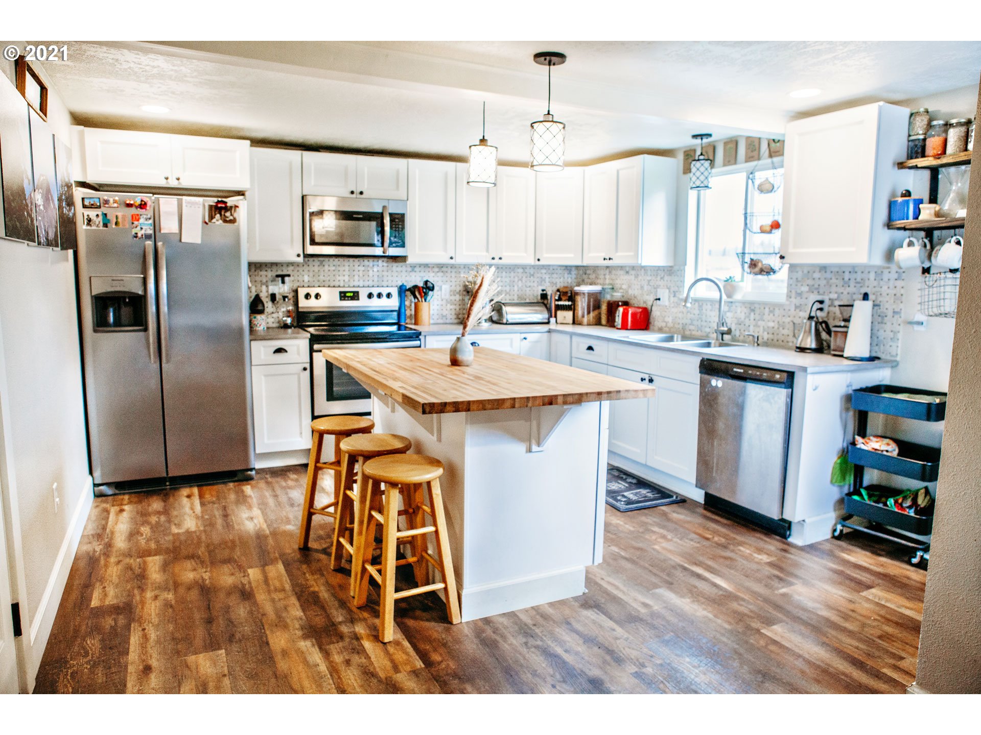 577 South 35th Street Springfield, OR 97478 - Photo 4 of 14 a kitchen with stainless steel appliances kitchen island granite countertop a refrigerator a stove a sink dishwasher and white cabinets with wooden floor