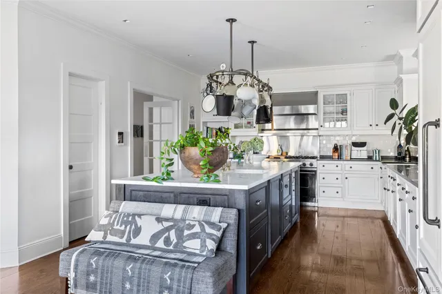 a kitchen with stainless steel appliances granite countertop a table chairs stove and white cabinets