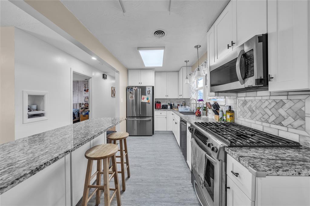 100 Rosedale Avenue Keene, TX 76059 - Photo 5 of 22 Kitchen featuring white cabinetry, light-toned flooring, stainless steel appliances, and granite countertops