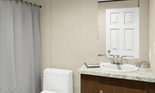 a bathroom with a granite countertop sink and a toilet