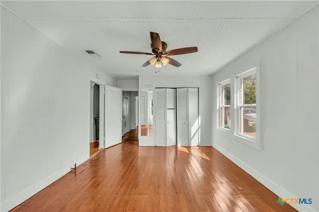 a view of an empty room with window and wooden floor