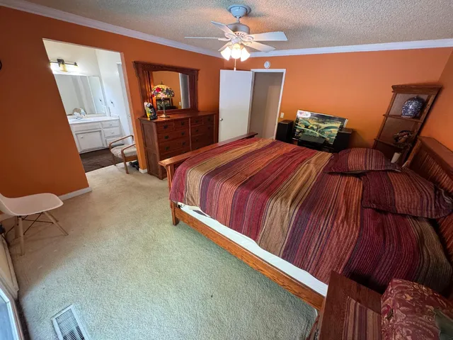 a bedroom with a bed dresser and a flat tv screen