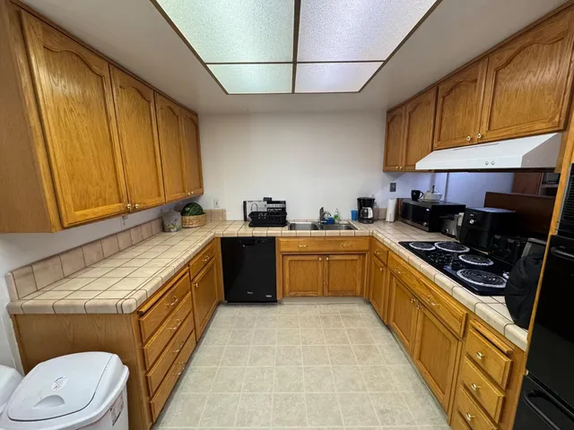 a kitchen with stainless steel appliances a sink a stove a refrigerator cabinets and a window
