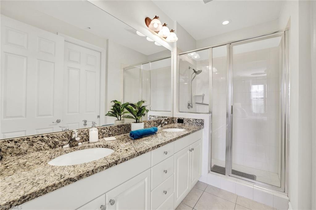 9115 Capistrano Street South, Unit 8207 Naples, FL 34113 - Photo 13 of 29 a bathroom with a granite countertop sink and a mirror