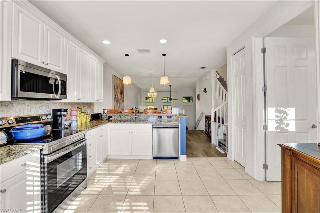 9115 Capistrano Street South, Unit 8207 Naples, FL 34113 - Photo 10 of 29 a kitchen with stainless steel appliances granite countertop a refrigerator a sink dishwasher a stove oven and white cabinets with wooden floor