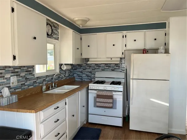 a kitchen with granite countertop a sink stove and refrigerator