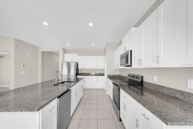 a large kitchen with stainless steel appliances granite countertop a sink stove and cabinets