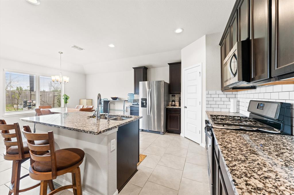 a kitchen with stainless steel appliances kitchen island granite countertop a stove refrigerator and cabinets