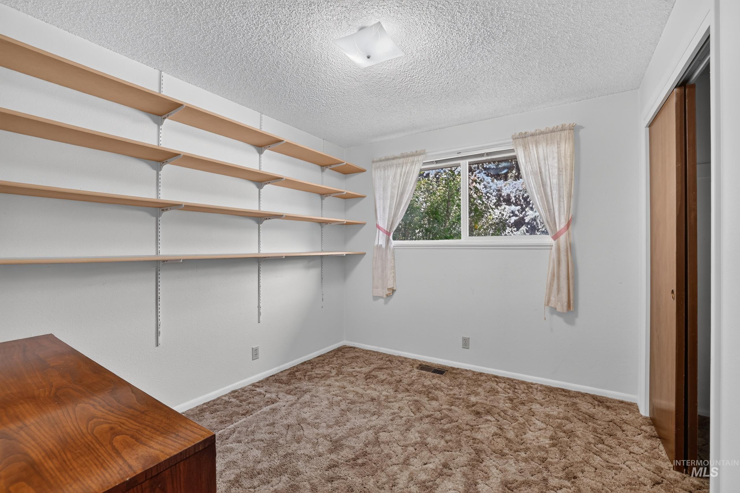 9055 West Highlander Road Boise, ID 83709 - Photo 24 of 39 Wall-mounted shelving system, broad window, and permanent closet with sliding doors