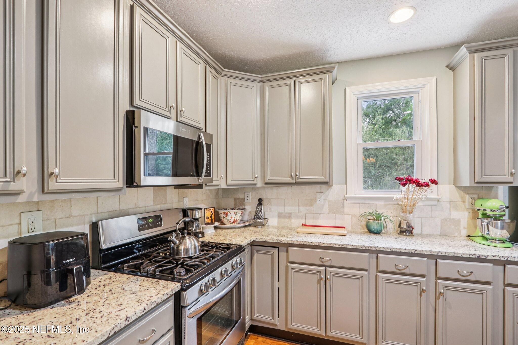 1605 Lorimier Road Jacksonville, FL 32207 - Photo 25 of 57 a kitchen with granite countertop a stove a sink and a white cabinets