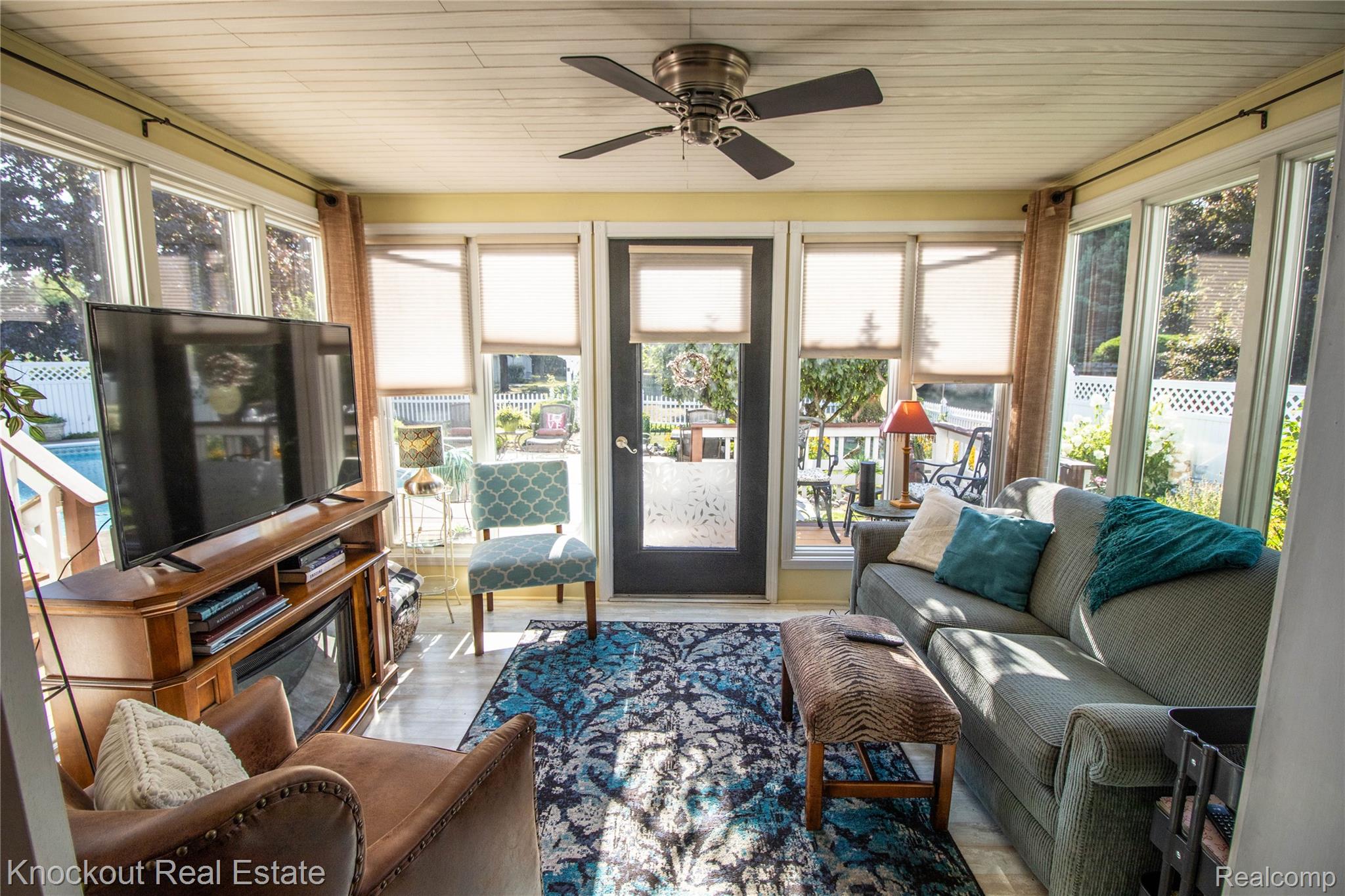 14720 Lincoln Road Chesaning, MI 48616 - Photo 12 of 60 Sunroom with extensive window walls, a ceiling fan, wood-finish flooring, and a built-in media console with an electric fireplace