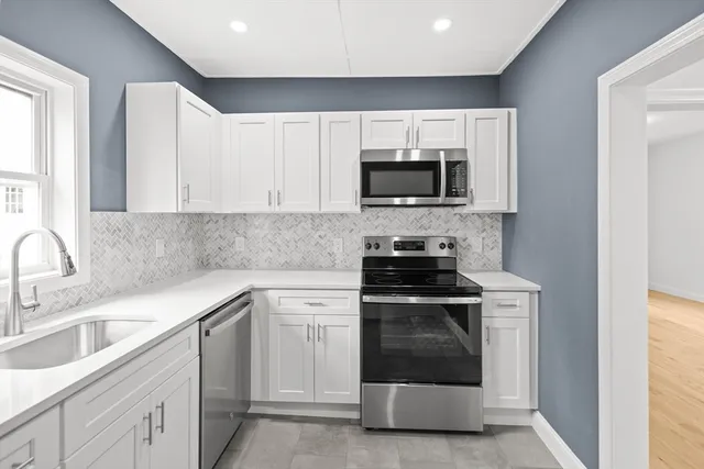 a kitchen with white cabinets appliances and sink