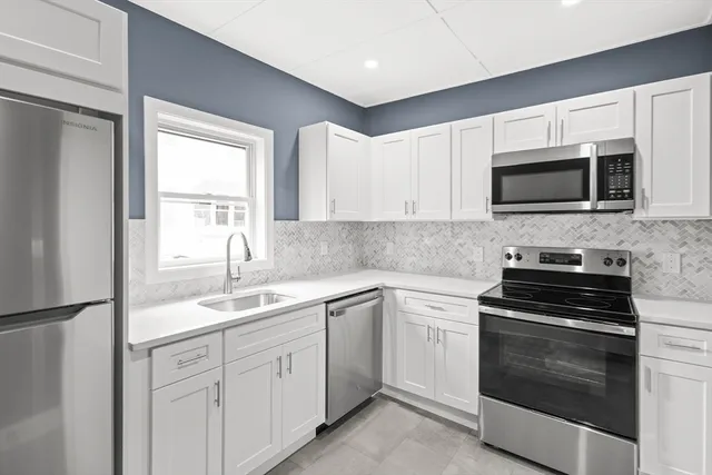 a kitchen with white cabinets and stainless steel appliances