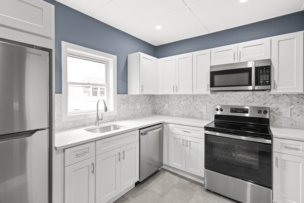 57 Ord Street Salem, MA 01970 - Photo 12 of 40 a kitchen with white cabinets and stainless steel appliances