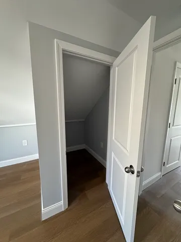 a view of a hallway with wooden floor and closet