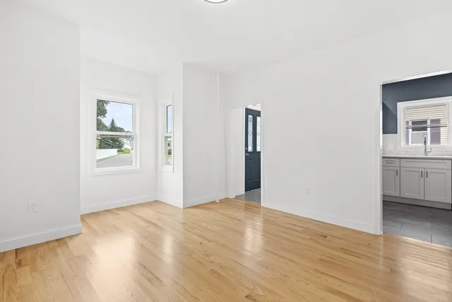 a view of an empty room with window and wooden floor