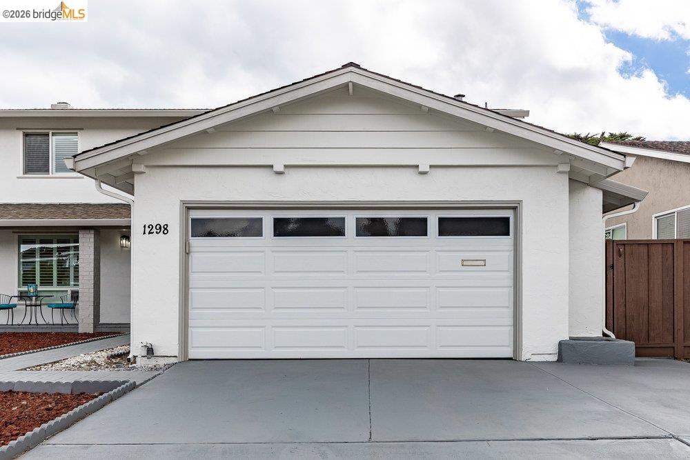1298 Ribbon Street Foster City, CA 94404 - Photo 10 of 86 Front exterior featuring a white paneled garage door with upper window inserts, a painted concrete driveway, and stucco siding
