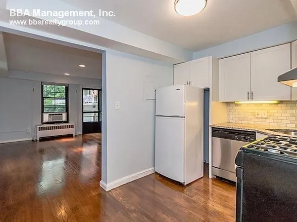 a kitchen with a refrigerator and wooden floor