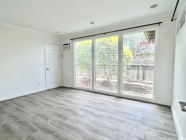 a view of an empty room with wooden floor and a window