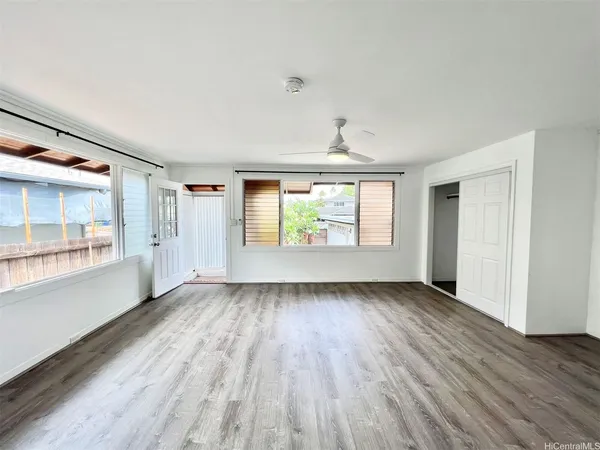 an empty room with wooden floor and windows
