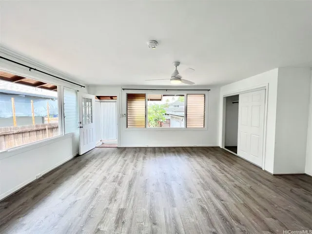 an empty room with wooden floor and windows