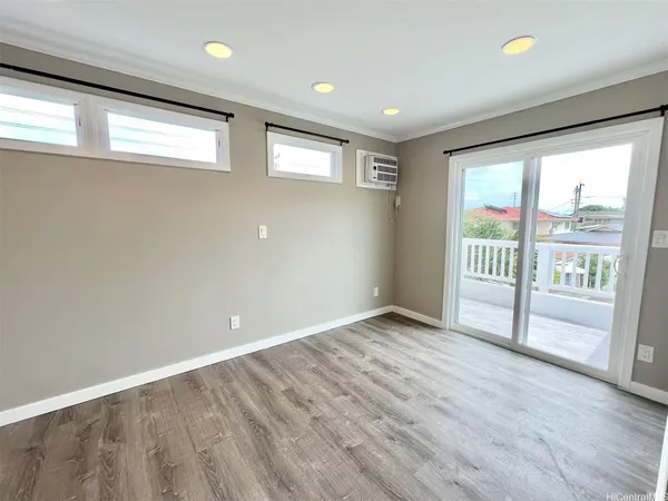 a view of an empty room with wooden floor and a window
