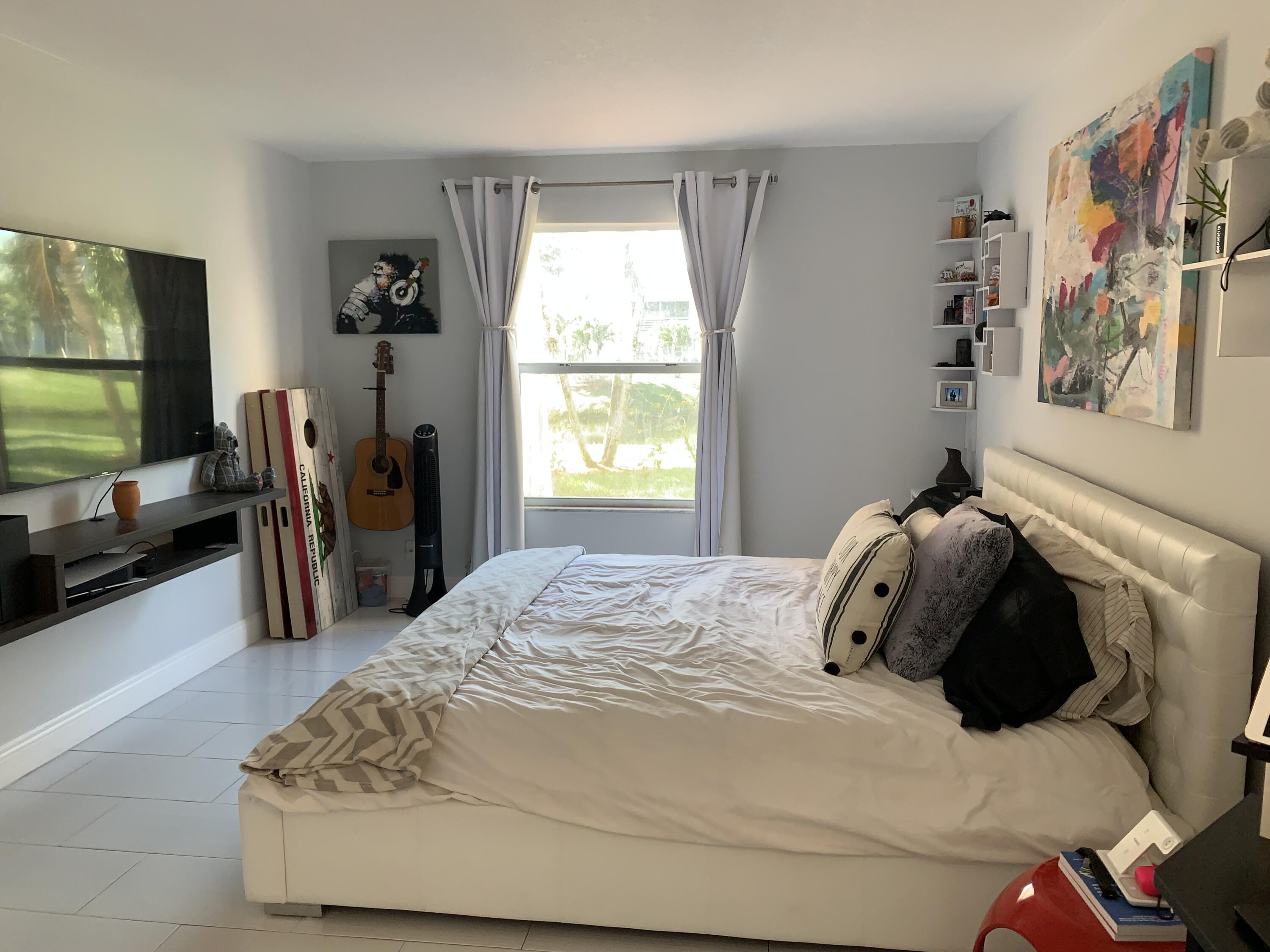 2500 Fiore Way, Unit 109 Delray Beach, FL 33445 - Photo 6 of 16 a bedroom with a bed and a flat tv screen on the dresser