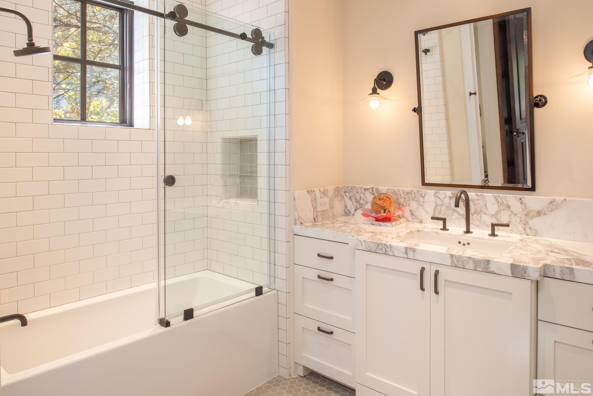 175 Hawken Road Reno, NV 89519 - Photo 37 of 40 a bathroom with a granite countertop sink a mirror a bathtub and shower