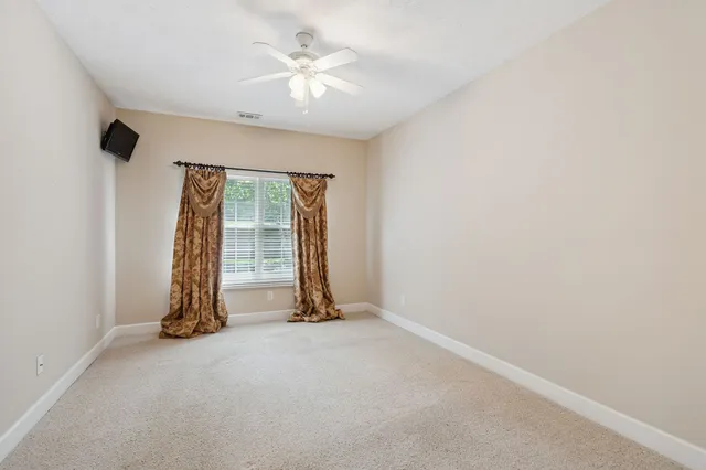 an empty room with a ceiling fan and a window