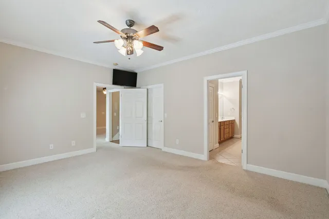 an empty room with chandelier fan and windows