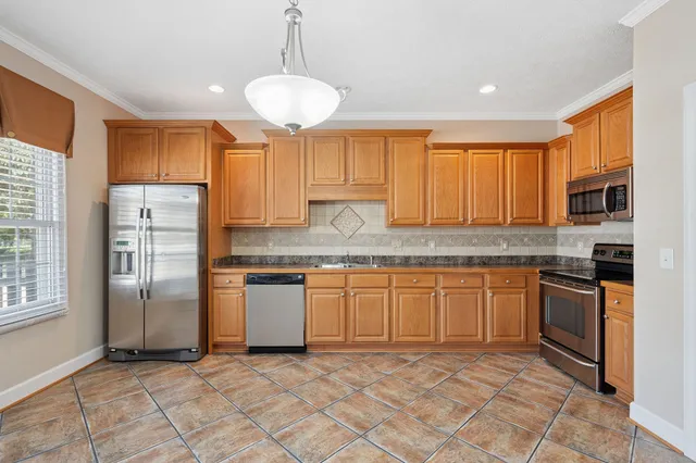 a kitchen with stainless steel appliances granite countertop a stove a sink and a refrigerator
