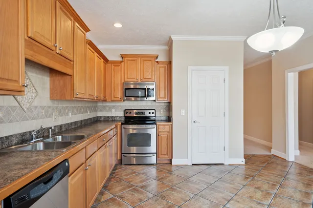 a kitchen with stainless steel appliances granite countertop a sink a stove a refrigerator cabinets and a counter top space