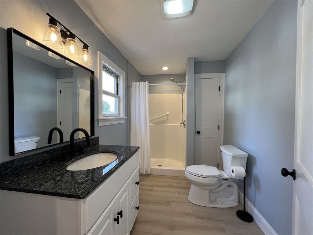 21 Brownville Avenue Ipswich, MA 01938 - Photo 10 of 20 a bathroom with a granite countertop sink a toilet a mirror and shower