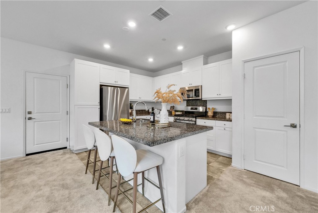 5584 Kate Way, Unit 10 Fontana, CA 92336 - Photo 6 of 42 a kitchen with stainless steel appliances a sink a stove a refrigerator cabinets and chairs