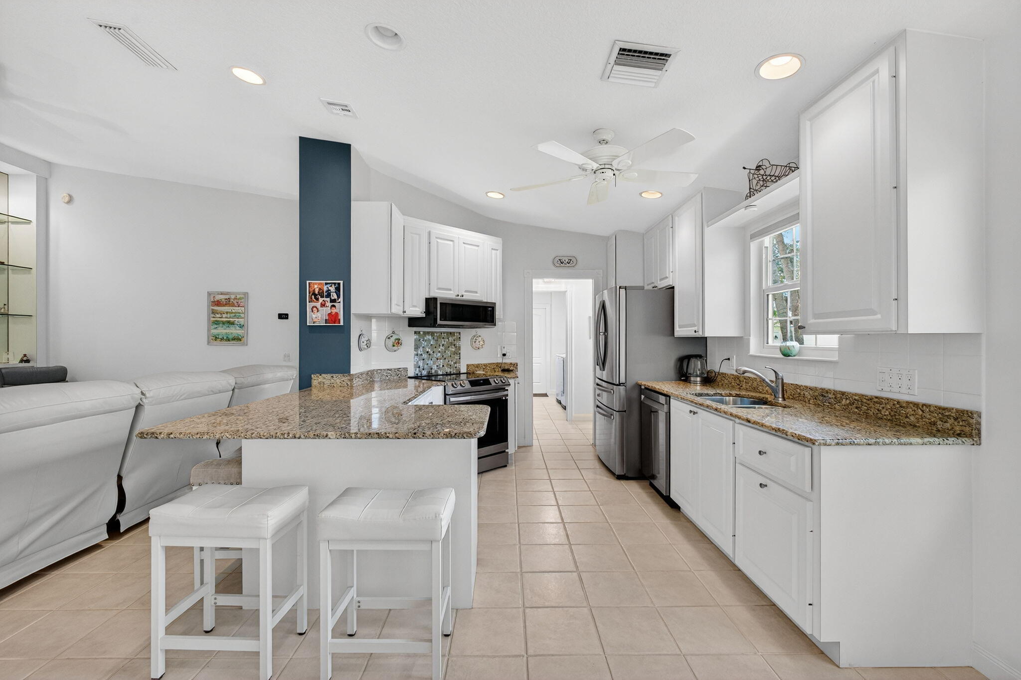 1035 Southwest Tamarrow Place Stuart, FL 34997 - Photo 6 of 42 a kitchen with stainless steel appliances kitchen island granite countertop a sink and cabinets