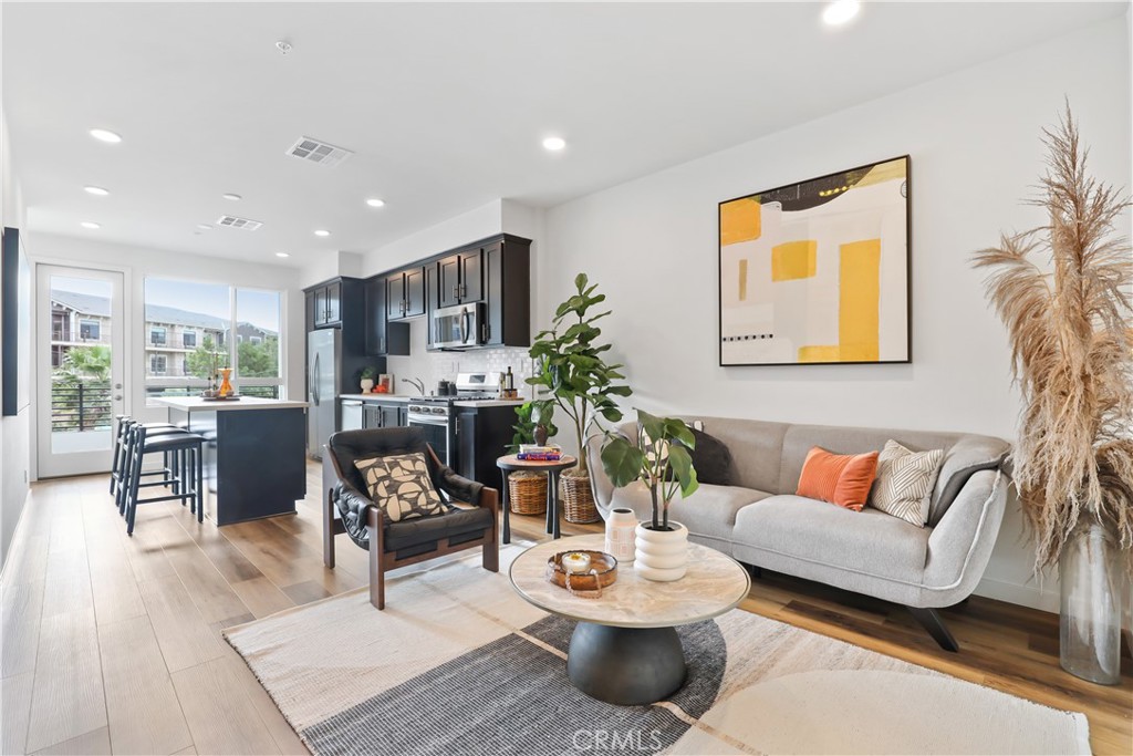 a living room with furniture kitchen view and a large window