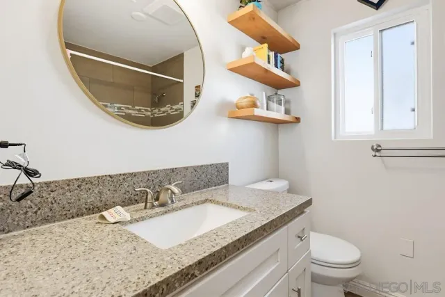 a bathroom with a granite countertop sink and a mirror