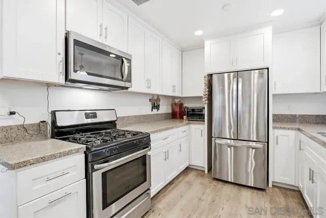 a kitchen with stainless steel appliances white cabinets a stove a sink and a refrigerator