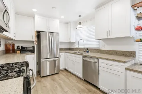 a kitchen with white cabinets and stainless steel appliances