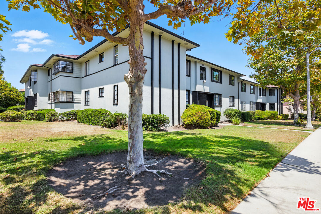 a front view of a house with garden and trees