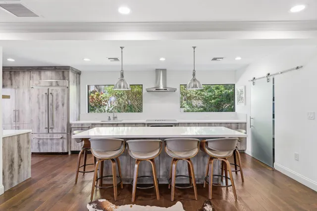 a room with stainless steel appliances kitchen island a table and chairs