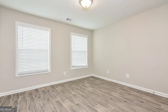 an empty room with wooden floor and windows