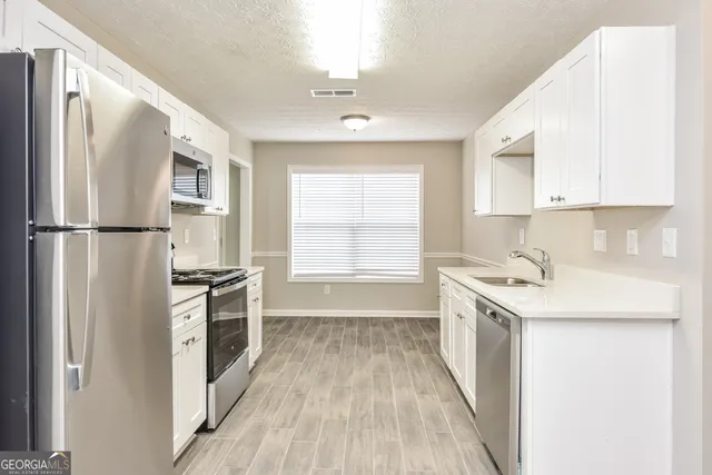 a kitchen with stainless steel appliances a stove a sink and a refrigerator