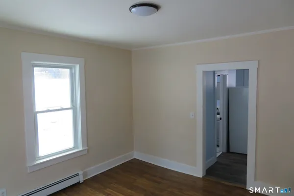 an empty room with wooden floor and window