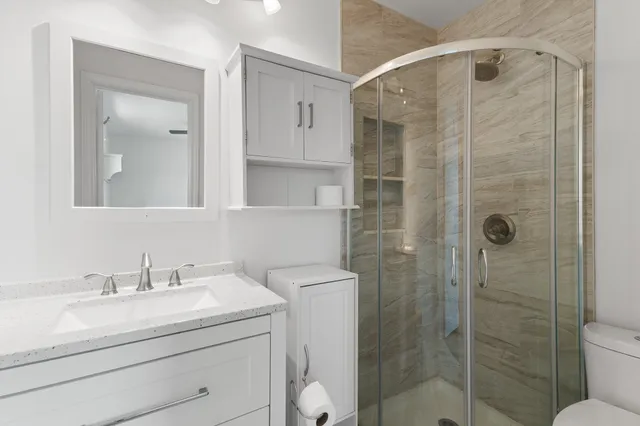 a bathroom with a shower sink vanity and toilet